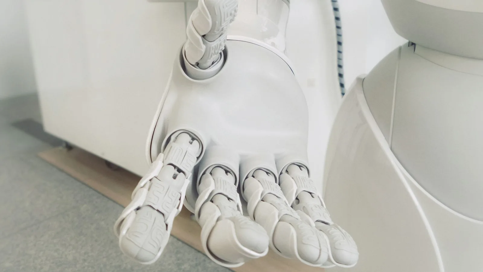 A white robotic hand resting on a light surface