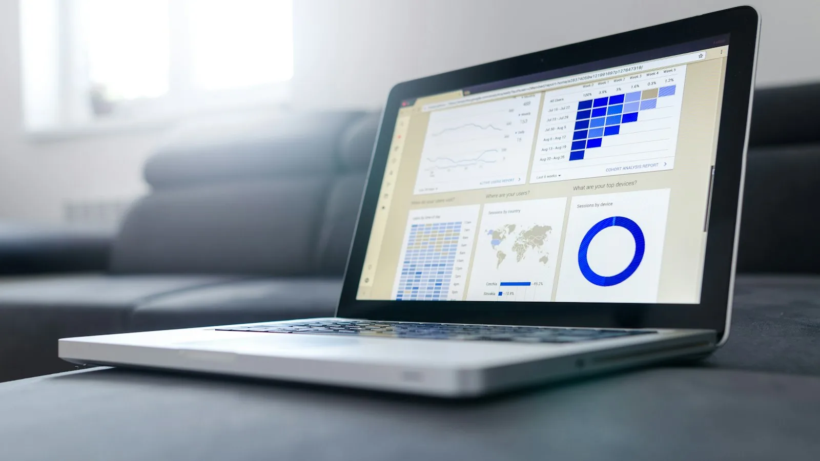 A laptop on a desk showing an analytics interface with charts and a map